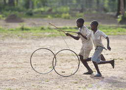 Boys roll bicycle wheels through a camp for for than 5,000 displaced people in Riimenze