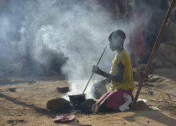 Eight-year old Adieu Anai cooks over a fire (photo: Caritas Internationalis).
